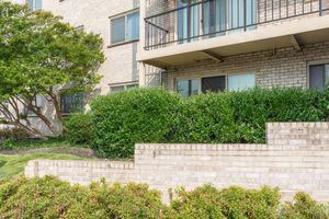 a house with bushes in front of a brick building