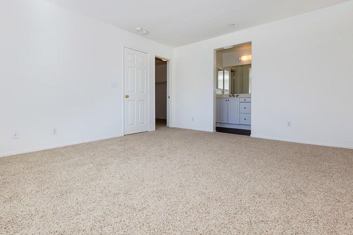 Carpeted bedroom with open bathroom door