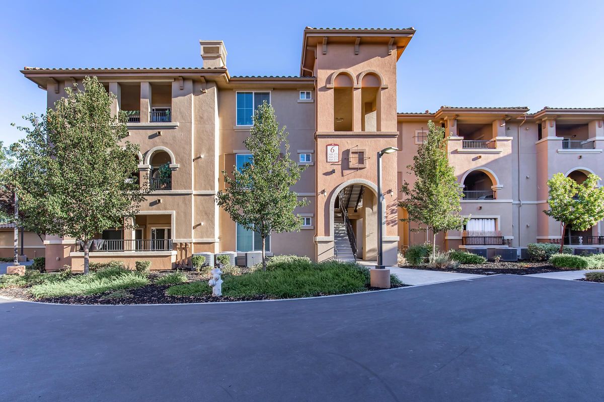 a house with bushes in front of a brick building