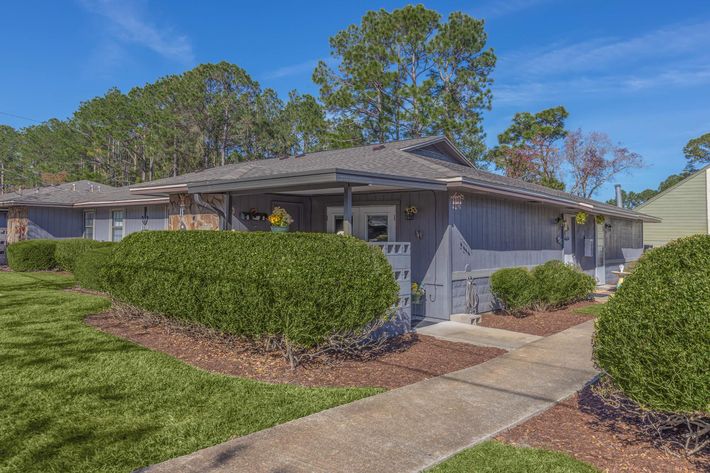 a house with bushes in front of a brick building