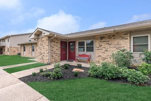 a house with a lawn in front of a brick building