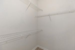 Empty closet with white wire shelving mounted on the walls. The walls are painted in a light color, and the floor appears to be a light-colored wood or laminate. There are no items or additional furniture in the space, creating a minimalistic and clean appearance.