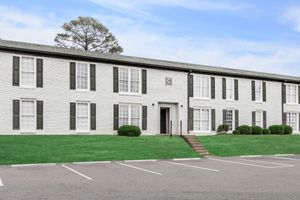 a large brick building with grass in front of a house