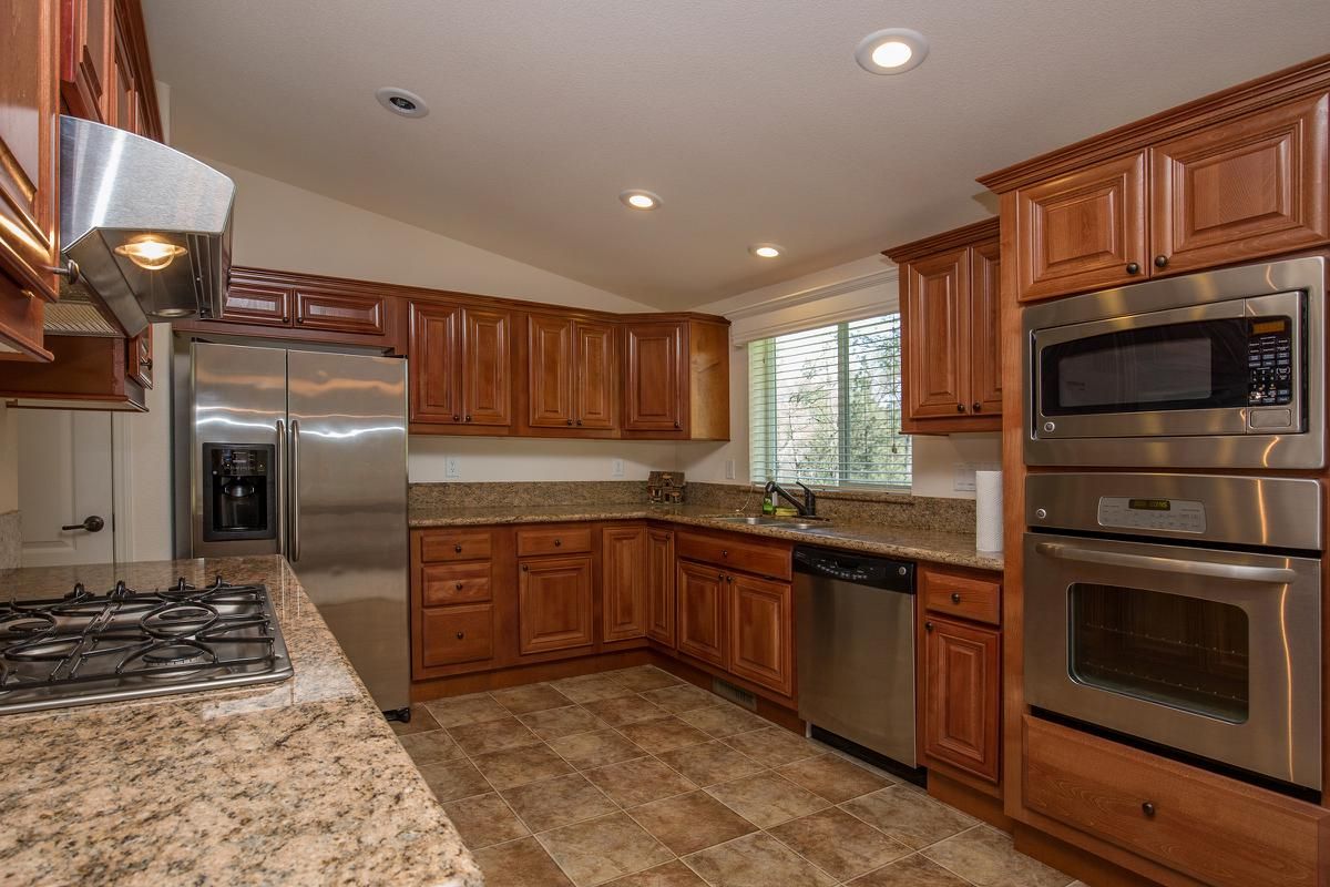 a large kitchen with stainless steel appliances and wooden cabinets