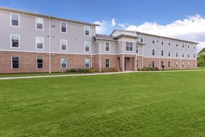 a large brick building with a grassy field