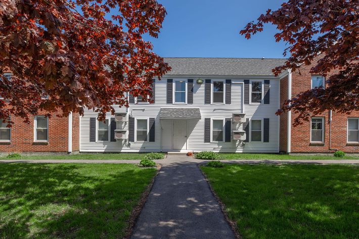 a large brick building with grass in front of a house