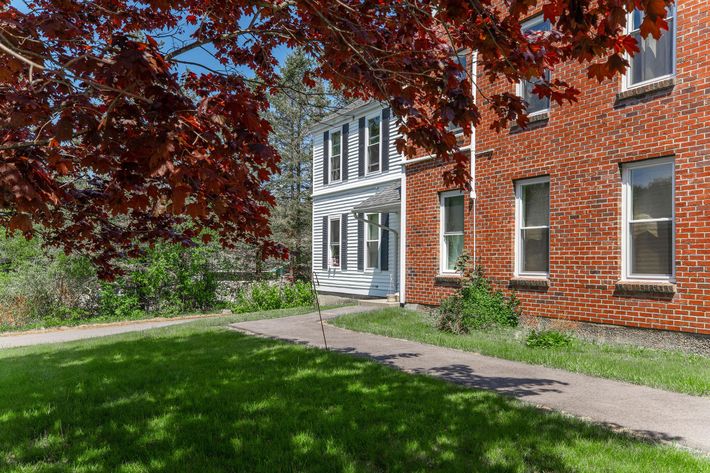 a large brick building with grass in front of a house