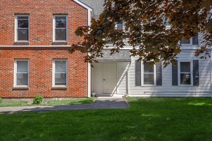 a large brick building with grass in front of a house