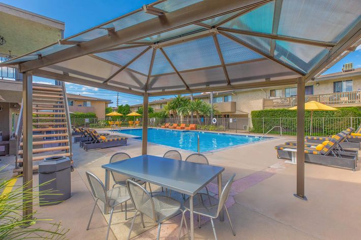 Vio Tustin community pool next to a table and chairs under glass pavilion