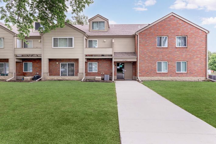 a house with a lawn in front of a brick building