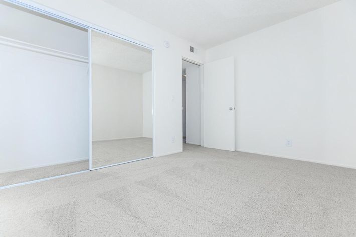 Unfurnished bedroom with sliding mirror glass closet doors