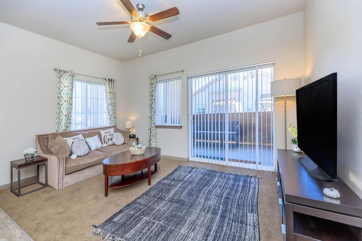 WELCOMING LIVING ROOM WITH BALCONY ACCESS AT CENTENNIAL PLACE APARTMENT HOMES