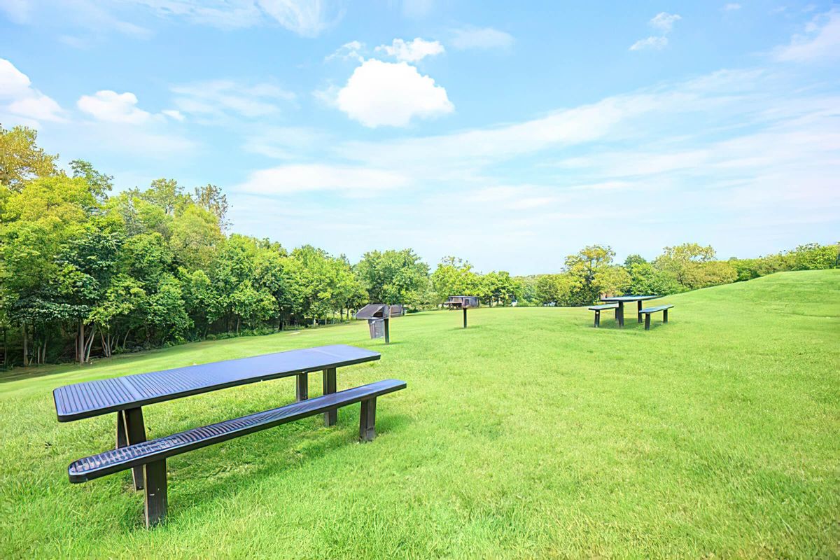 an empty park bench sitting on top of a lush green field
