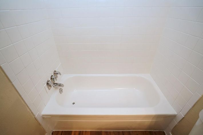 a white tub sitting next to a tiled wall