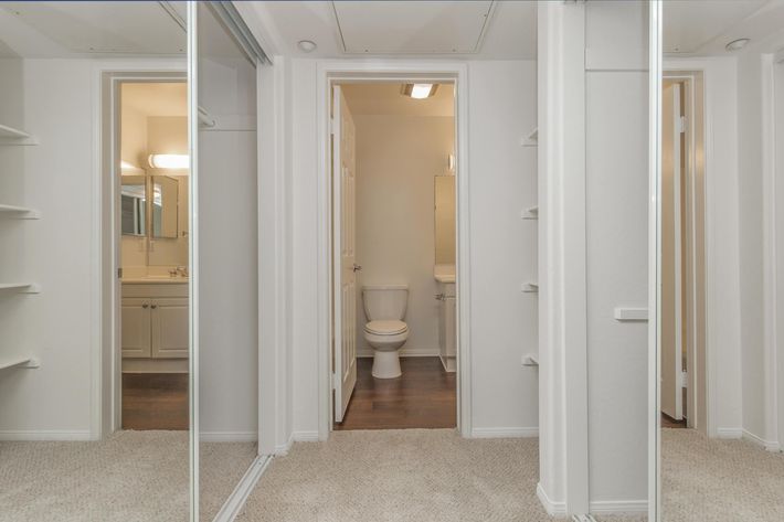 Open bathroom door with two sets of sliding glass mirror closet doors