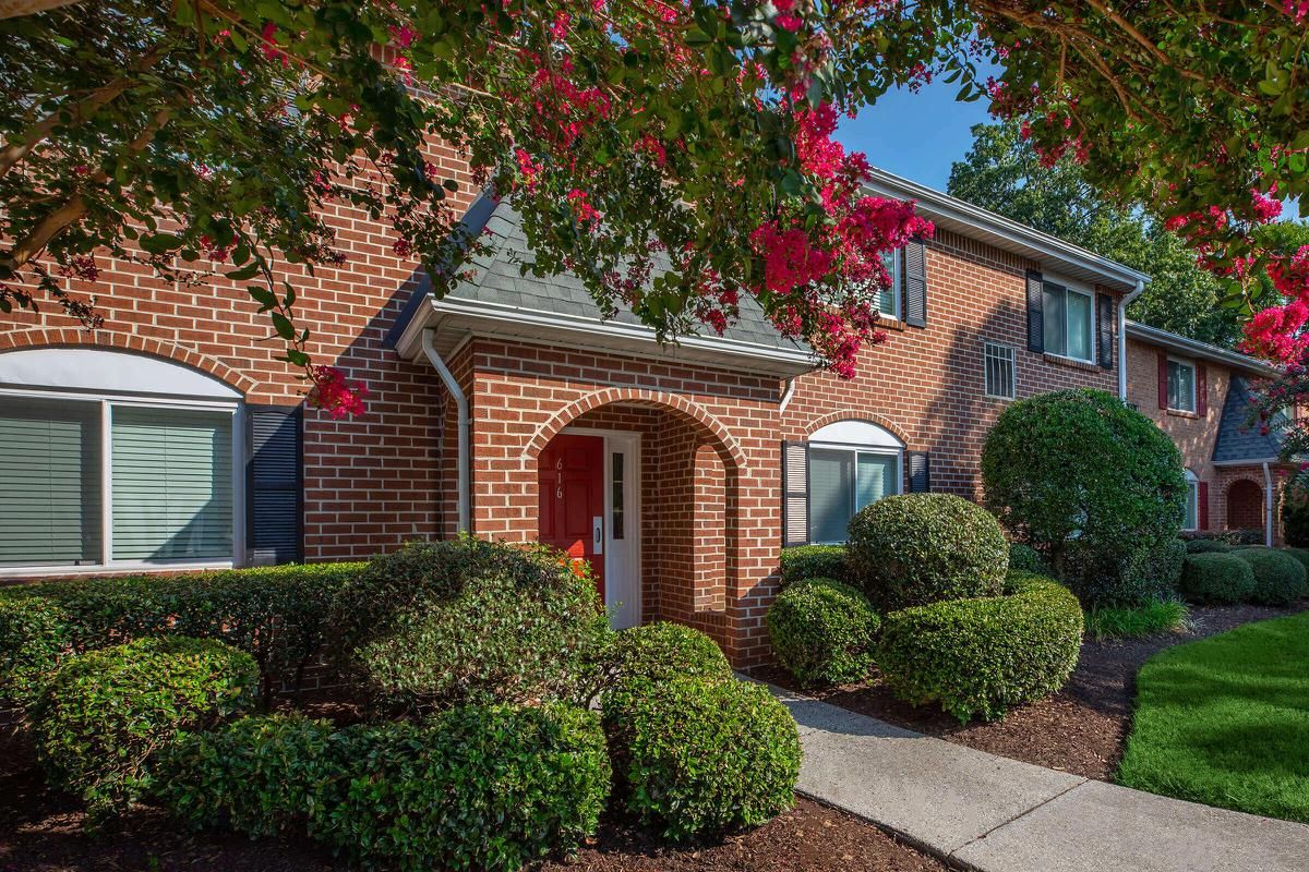 a house with bushes in front of a brick building