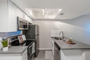 Galley way kitchen with stainless steel appliances and grey quartz countertops