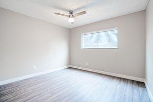 Large open bedroom with ceiling fan and small window