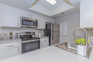 White modern kitchen space with white cabinets, stainless steel appliances, and light grey counters