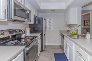 White modern kitchen space with white cabinets, stainless steel appliances, and light grey counters