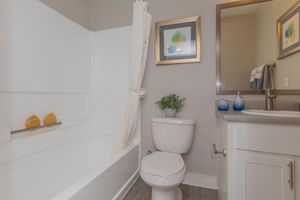 Clean bathroom with shower, tub, toilet, and mirrored sink vanity