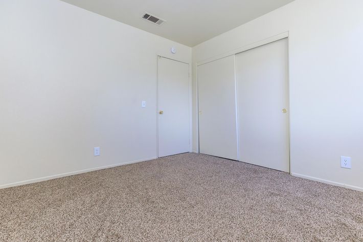 Vacant bedroom with carpet and sliding closet doors