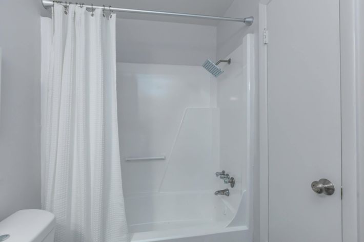 a white tub sitting next to a shower curtain