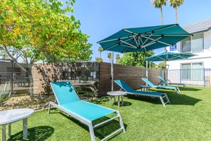 Outdoor grass area with tanning pool chairs and sun shade covers
