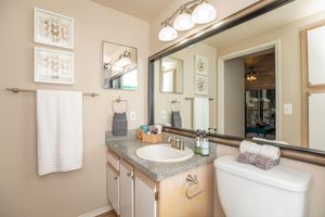 a furnished bathroom with wall length mirror