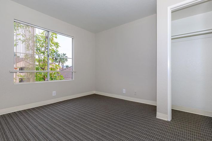 Carpeted bedroom with open window blinds