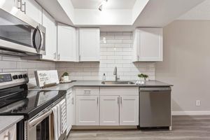 Open kitchen with white cabinets, white subway tile backsplash, and grey quartz countertops