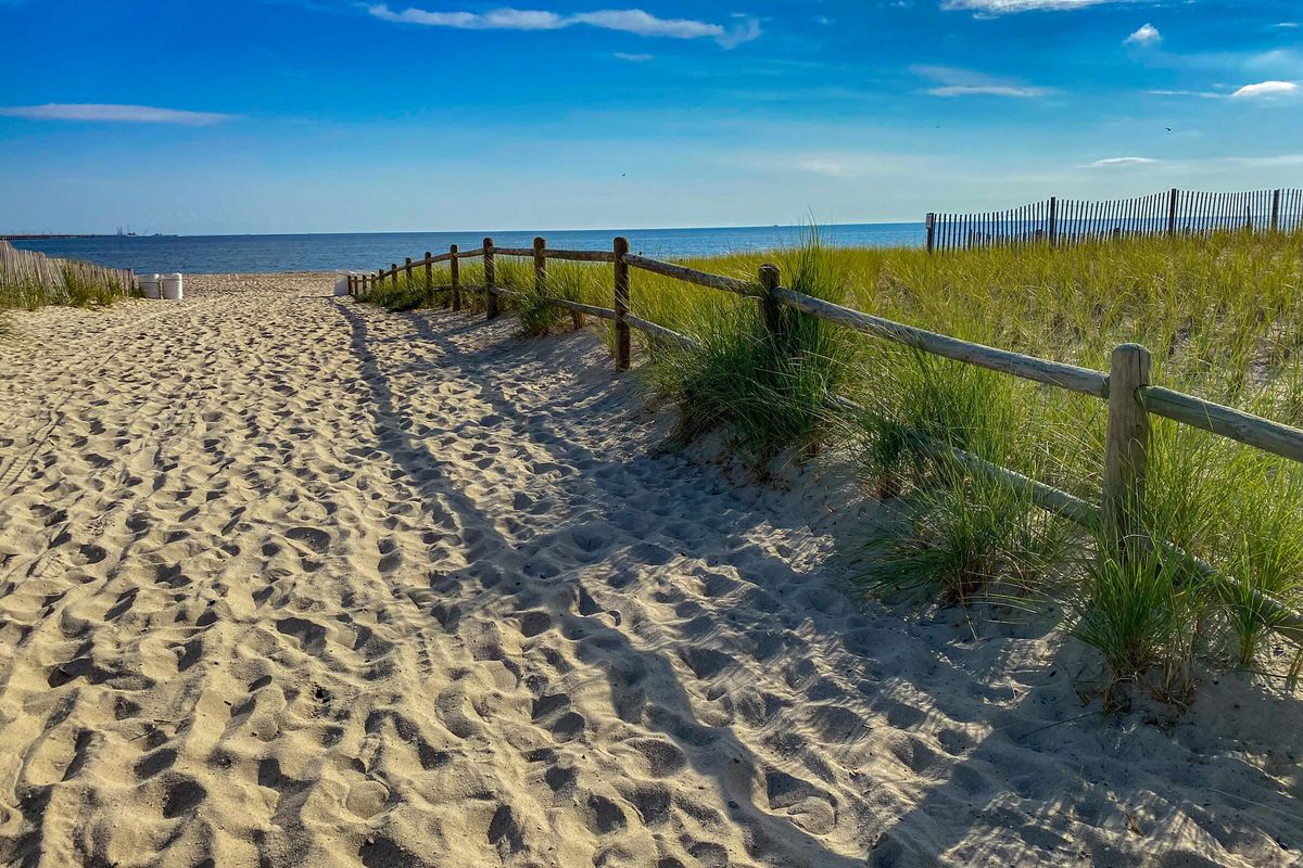 a sandy beach next to the fence