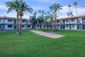 Apartment building grass court yard with horse shoe game and palm trees