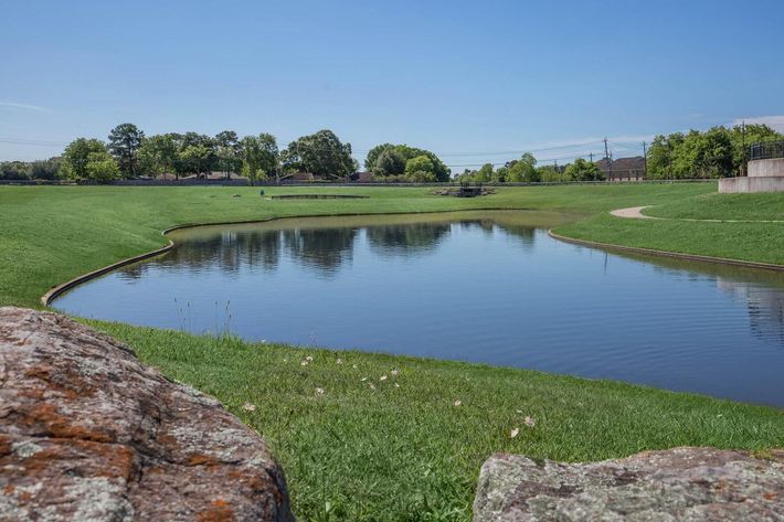 a pond next to a body of water with The Golf Club at Harbor Shores in the background