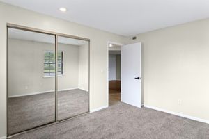 Gold carpeted bedroom interior and mirrored closet at The Arbor Apartments in Blue Springs, Missouri