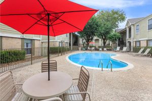 a red umbrella in front of a pool
