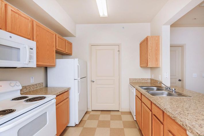 a kitchen with a stove a sink and a microwave oven above a refrigerator