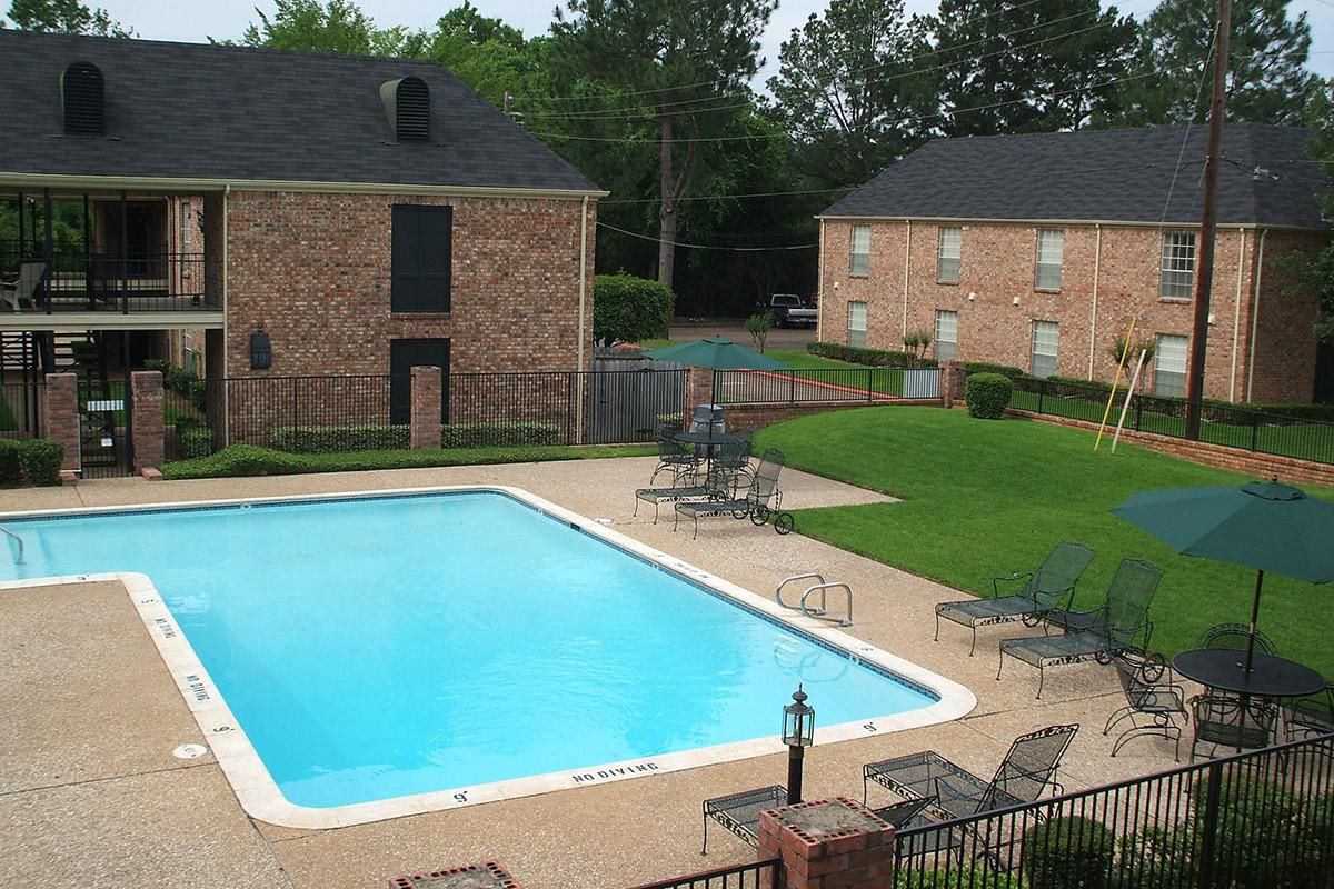 a house with a pool in front of a brick building