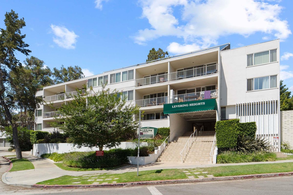 A modern three-story apartment building named "Levering Heights," featuring a green awning, multiple balconies, and landscaped greenery in front. The entrance has stairs leading up from the sidewalk.