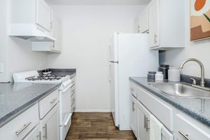 Galley way kitchen with white  cabinets, white appliances, and grey counter tops