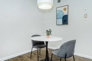 Dining room space with small round table, 2 grey chairs, and modern lighting fixture