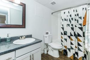Clean bathroom with colorful shower curtain, toilet, and vanity