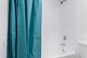 White shower and tub space with blue shower curtain