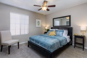 Large apartment bedroom with big bed in center of room and a large window
