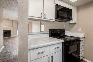 Apartment kitchen with white cabinets, black appliances, and a small window over the sink