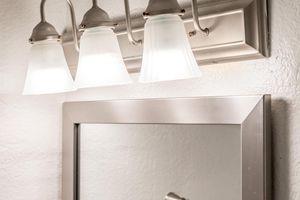Close up view of 3 piece light fixture above a mirror