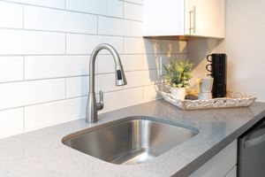 Close up of silver sink and faucet in grey quartz countertops