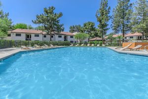 Pet-Friendly Apartments in Phoenix AZ - Tides on 71st - Building Exterior with Pool and Poolside Seating and Fence