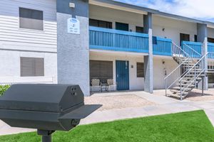 Exterior of a 2 story apartment building next to a charcoal grill