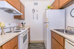 Galley way kitchen with cherry wood cabinets, white appliances, and cream colored countertops